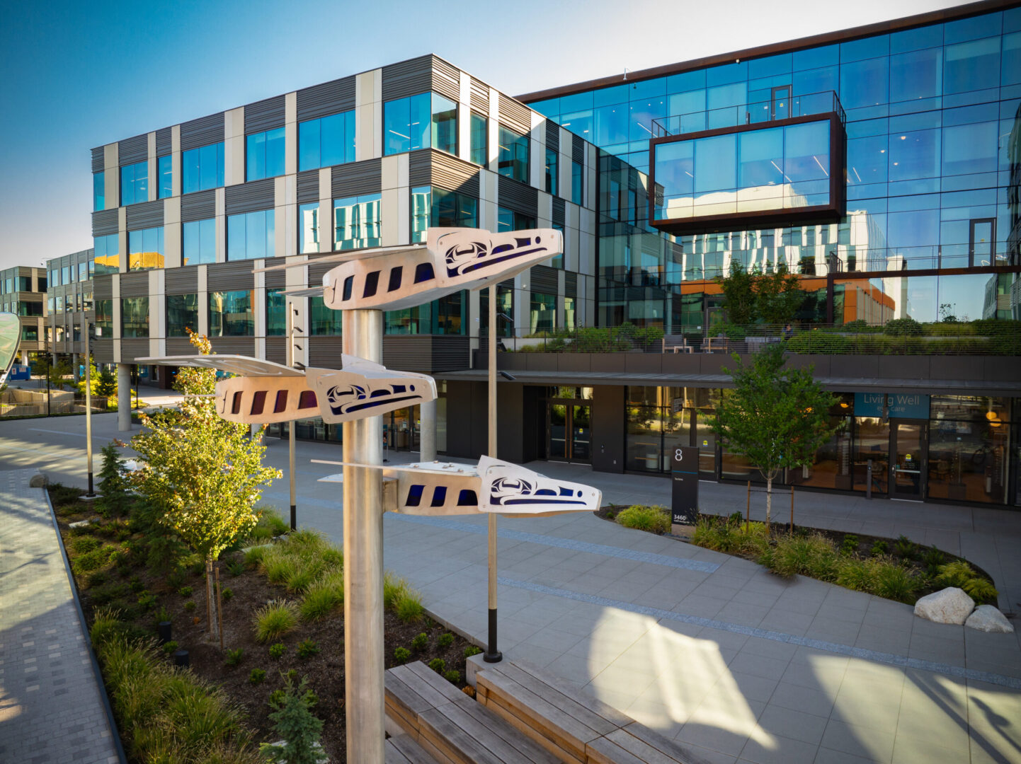 A steel and glass sculpture of ravens suspended on a pole near a new office building