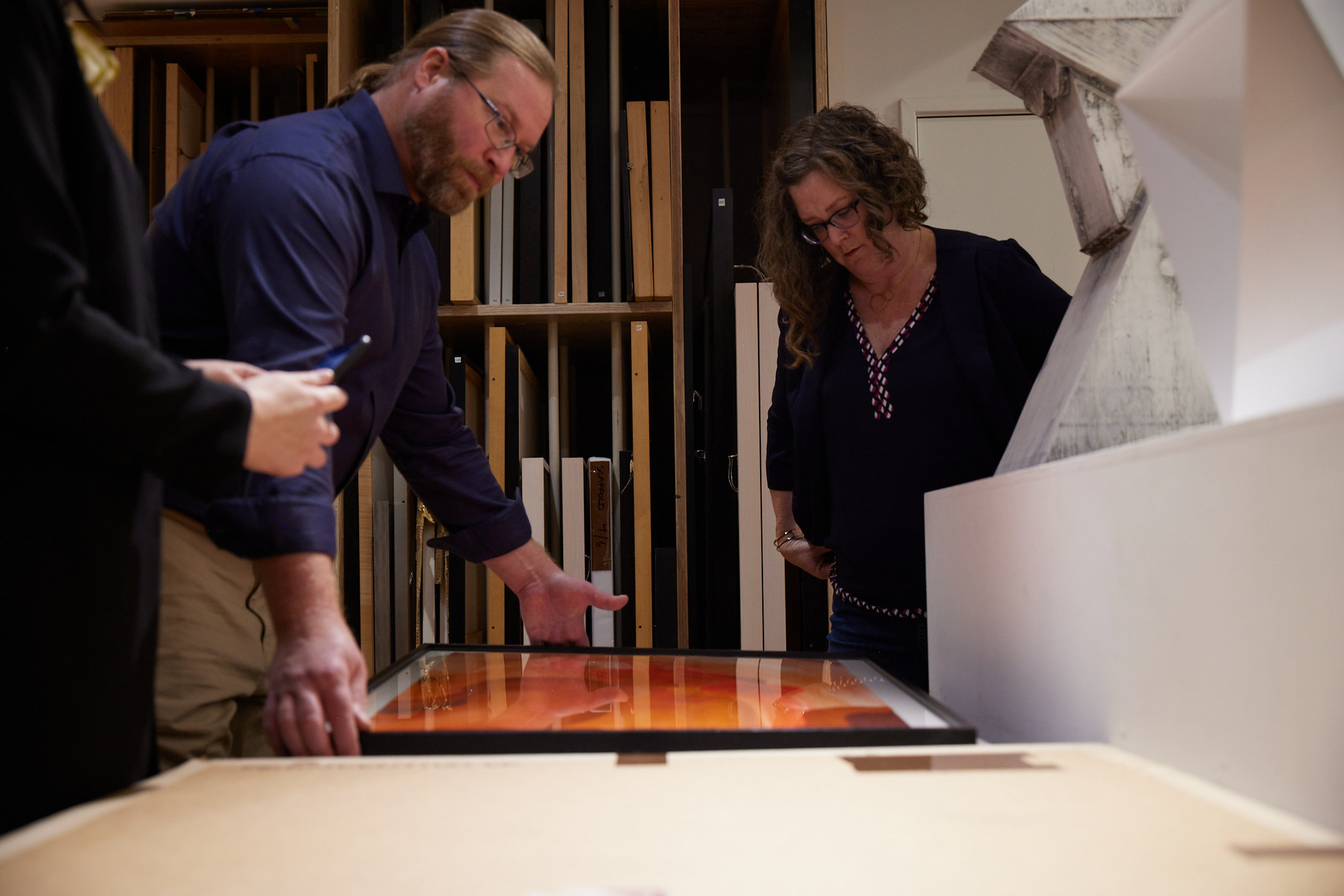 A man and woman look at an artwork laid on a table